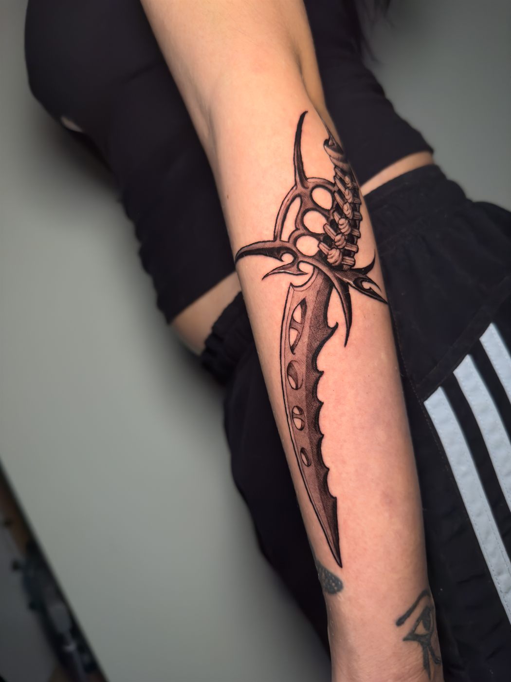 Daga orgánica de columna vertebral tatuada en antebrazo, black and gray