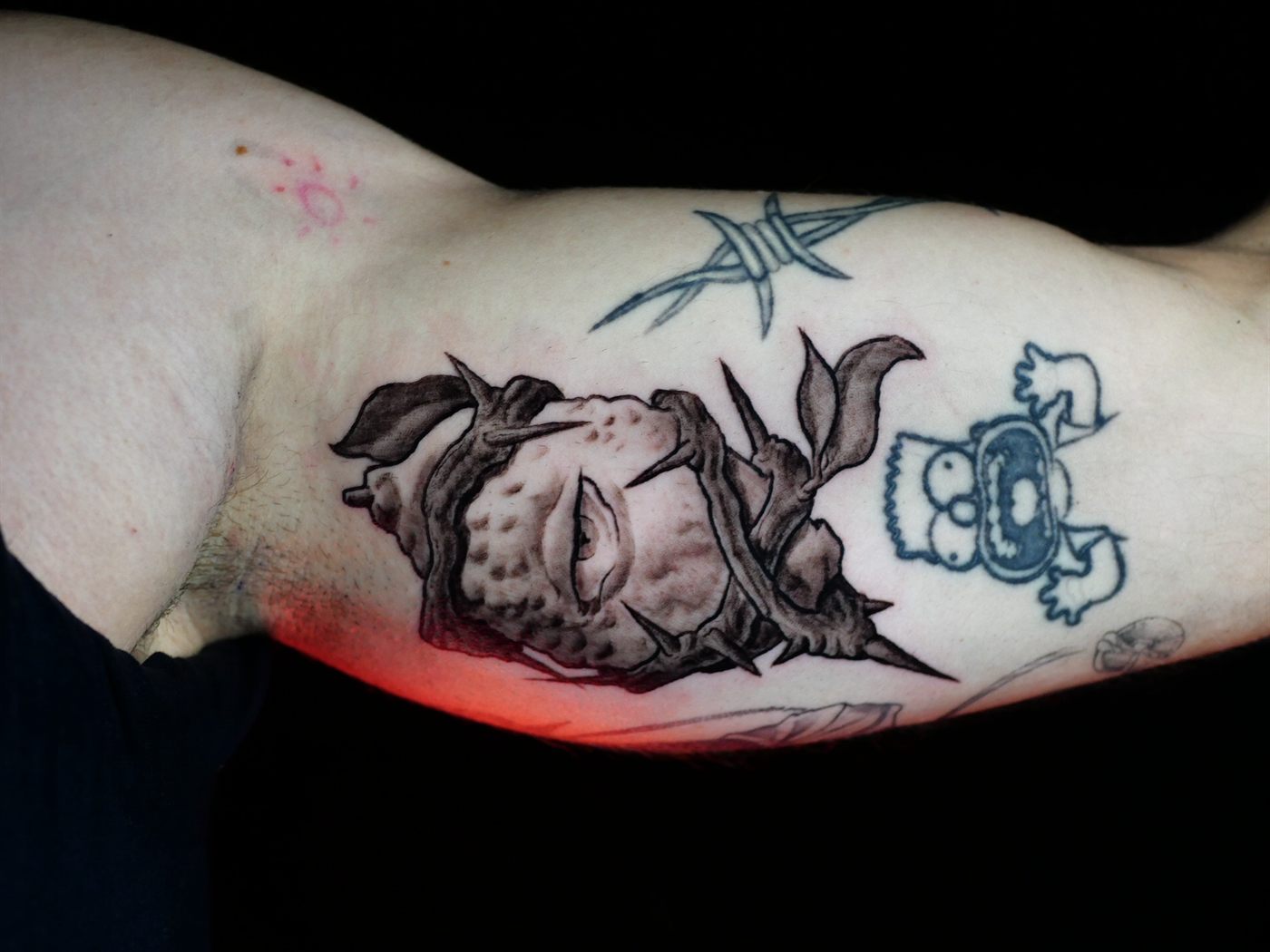 Criatura ilustrativa con espinas tatuada en bíceps