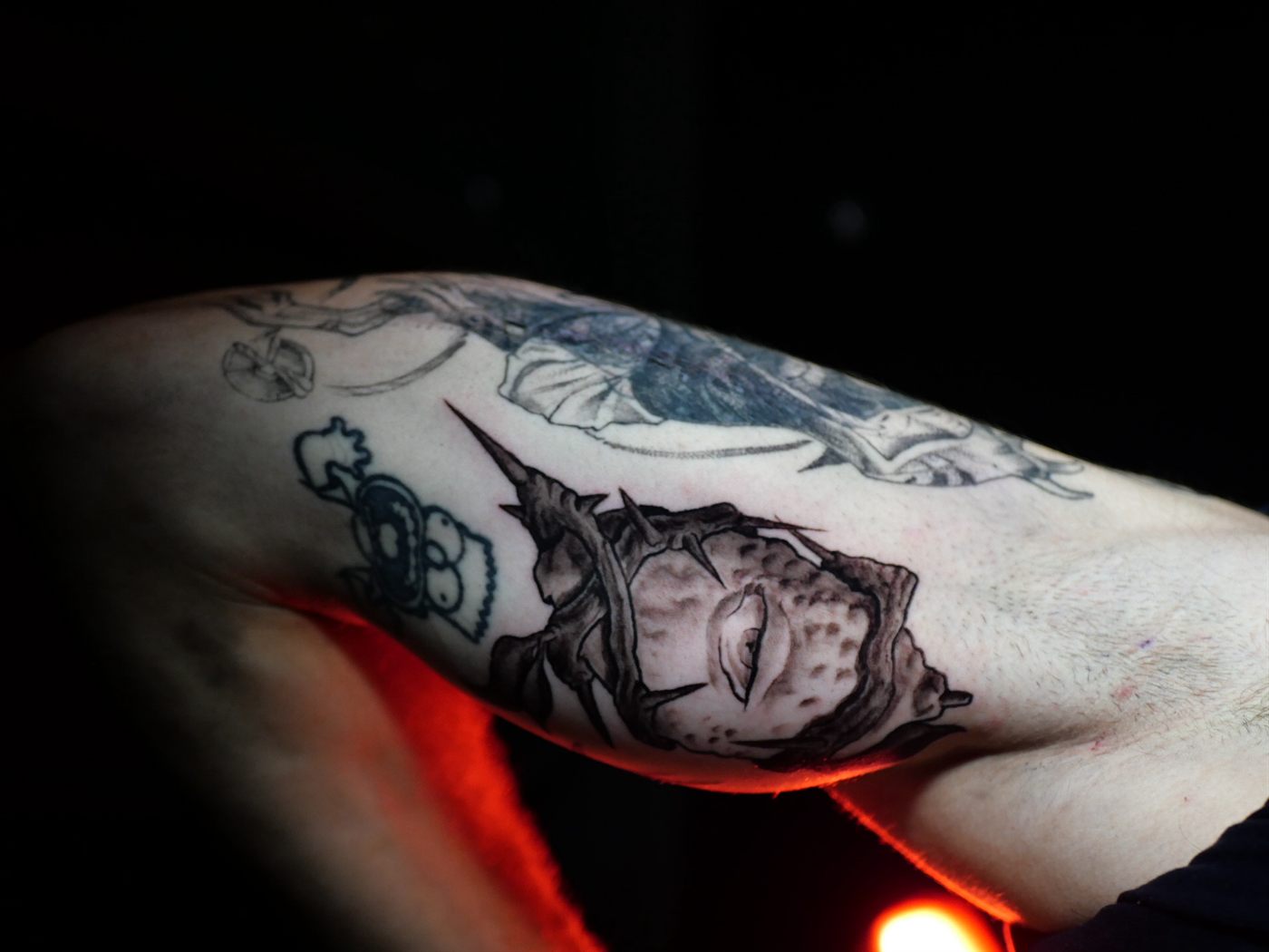 Criatura oscura ilustrativa tatuada en la cara interna del brazo